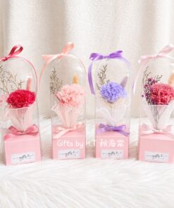 A preserved carnation flower arranged with dried florals inside a clear display box, finished with ribbon accents, designed as an elegant Mother’s Day gift.