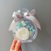 Preserved flower bottle with white rose and blue hydrangea arrangement