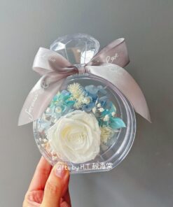 Preserved flower bottle with white rose and blue hydrangea arrangement